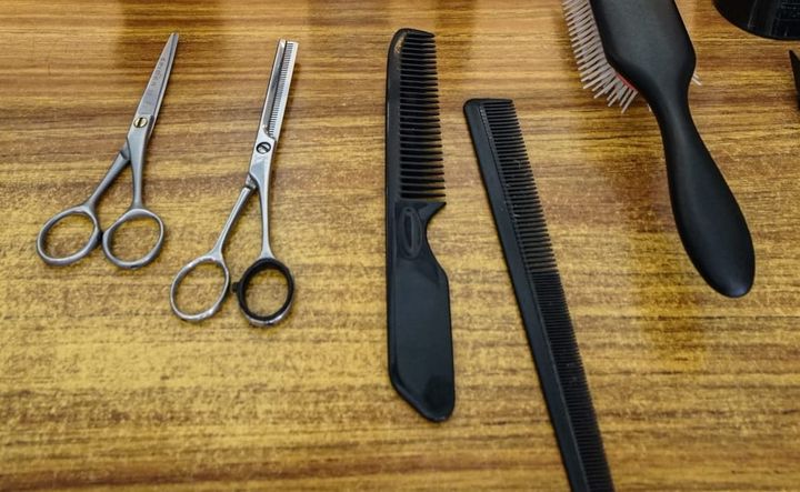 Two pairs of scissors, two combs and a hairbrush on a wooden counter
